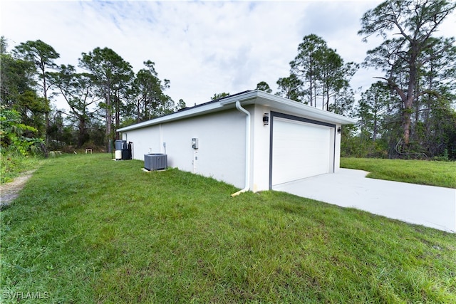 view of side of property featuring a lawn, cooling unit, and a garage