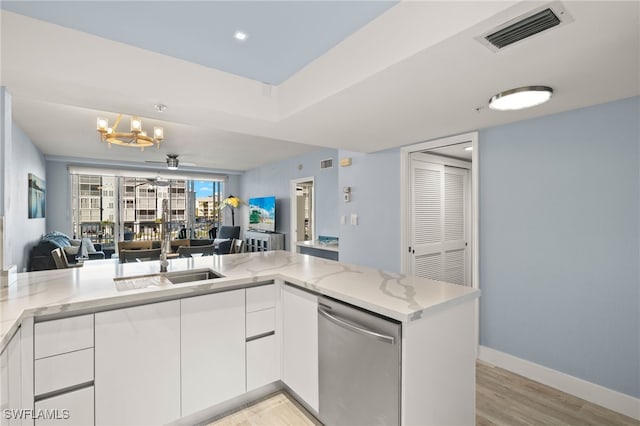 kitchen with ceiling fan with notable chandelier, dishwasher, white cabinets, kitchen peninsula, and light stone countertops