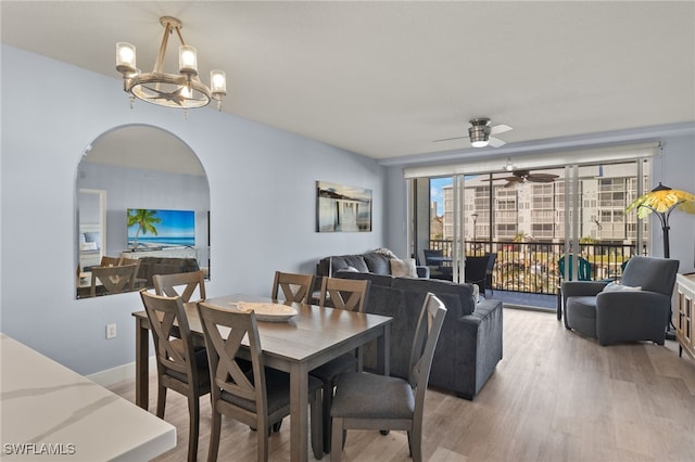 dining area with ceiling fan with notable chandelier and light hardwood / wood-style flooring