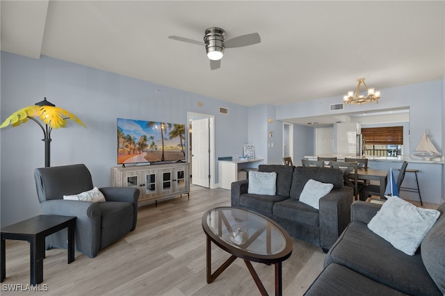 living room with ceiling fan with notable chandelier and light wood-type flooring