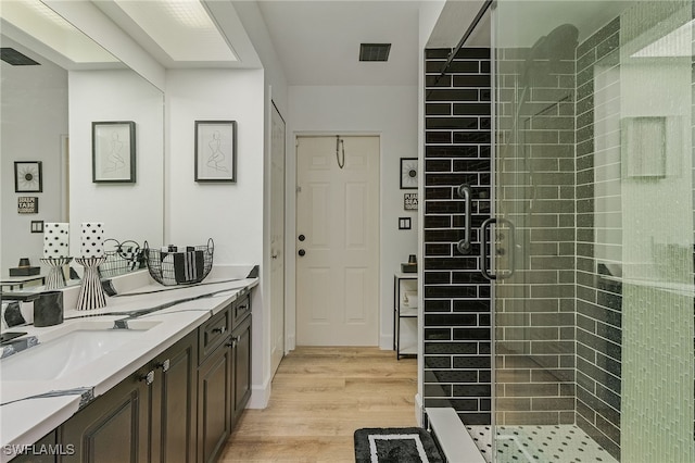 bathroom featuring hardwood / wood-style floors, tiled shower, and vanity