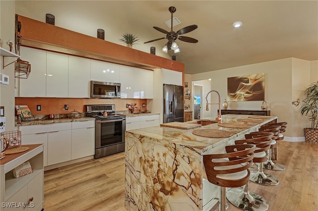 kitchen featuring ceiling fan, white cabinets, and stainless steel appliances