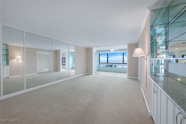 unfurnished living room featuring light colored carpet and crown molding