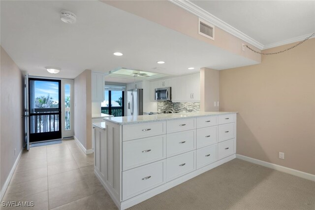 kitchen with white cabinets, appliances with stainless steel finishes, backsplash, ornamental molding, and kitchen peninsula