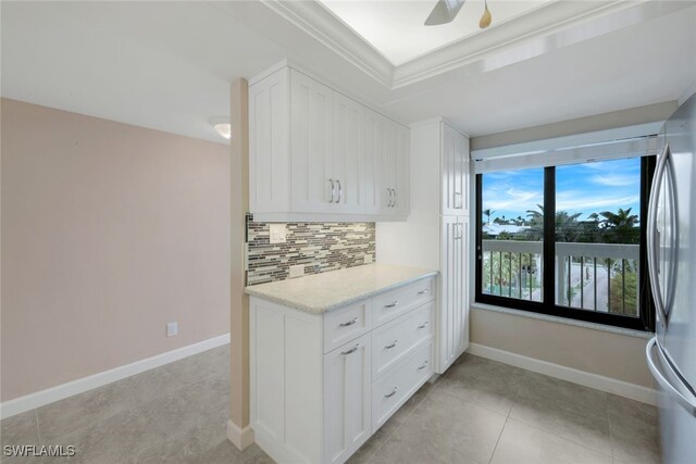 kitchen featuring light stone countertops, white cabinetry, white fridge, tasteful backsplash, and ceiling fan