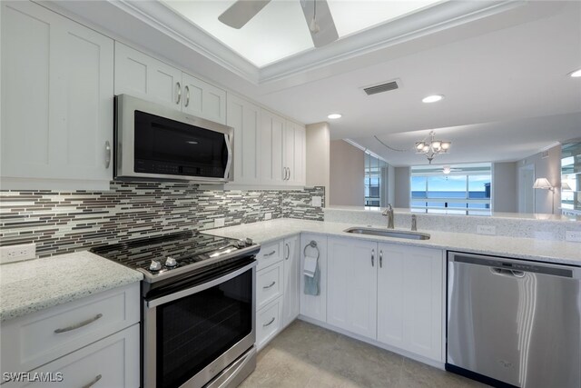 kitchen featuring kitchen peninsula, sink, white cabinetry, stainless steel appliances, and light stone counters