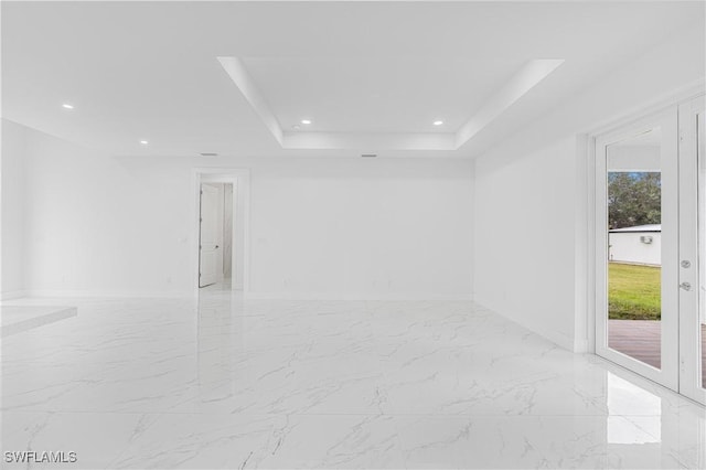 unfurnished room with a healthy amount of sunlight and a tray ceiling