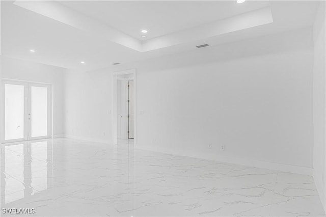 empty room featuring a raised ceiling and french doors