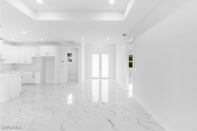 unfurnished living room with a raised ceiling and french doors