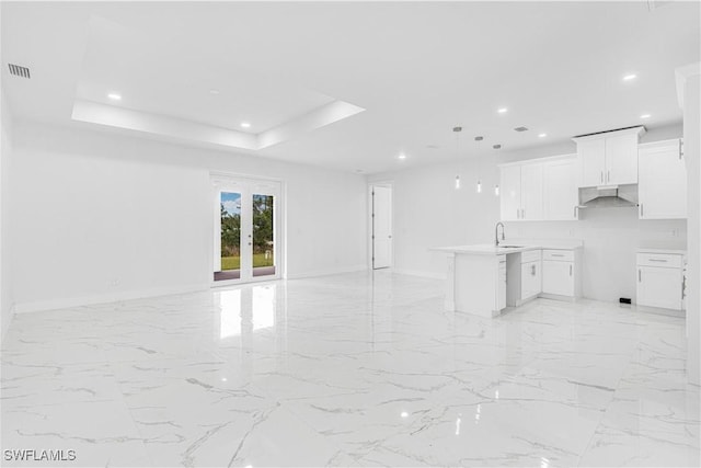 interior space featuring decorative light fixtures, white cabinets, a tray ceiling, and sink