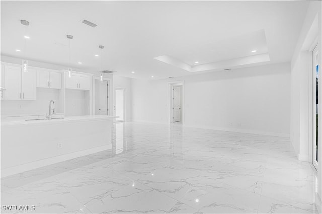 unfurnished living room featuring a tray ceiling and sink