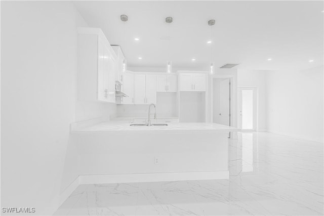 interior space with white cabinets, decorative light fixtures, sink, ventilation hood, and kitchen peninsula