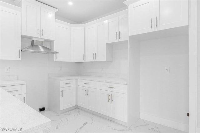 kitchen featuring wall chimney exhaust hood and white cabinetry