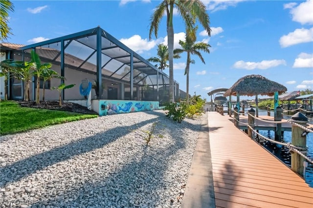 view of dock featuring a water view, a gazebo, a yard, and glass enclosure