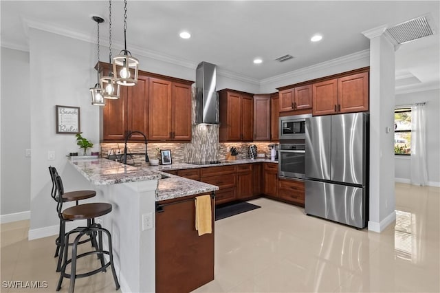 kitchen with pendant lighting, wall chimney range hood, a breakfast bar, appliances with stainless steel finishes, and kitchen peninsula