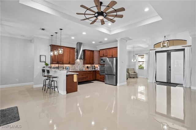 kitchen with a breakfast bar, appliances with stainless steel finishes, backsplash, decorative light fixtures, and wall chimney exhaust hood