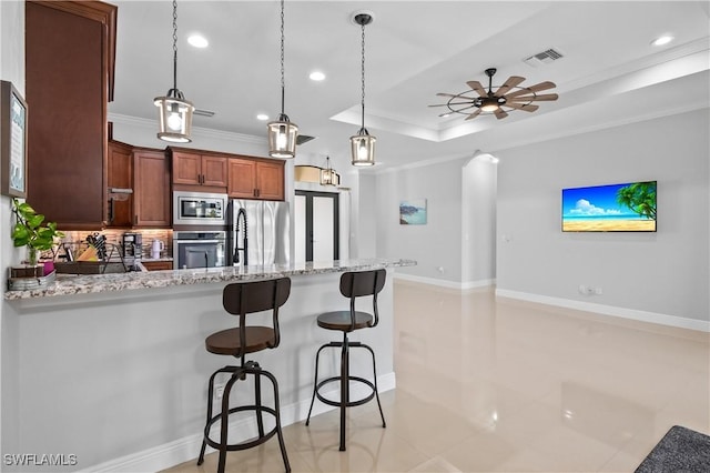 kitchen featuring decorative light fixtures, tasteful backsplash, ceiling fan, a tray ceiling, and stainless steel appliances