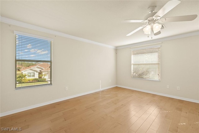 spare room featuring crown molding, a healthy amount of sunlight, baseboards, and light wood-style floors