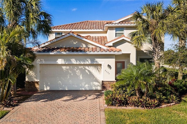 mediterranean / spanish home with a garage, decorative driveway, a tile roof, and stucco siding