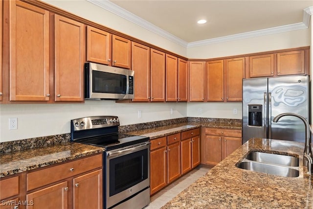 kitchen featuring a sink, appliances with stainless steel finishes, ornamental molding, brown cabinets, and dark stone counters