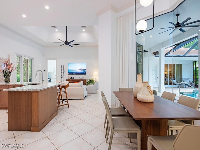 tiled dining area with sink, a tray ceiling, and ceiling fan