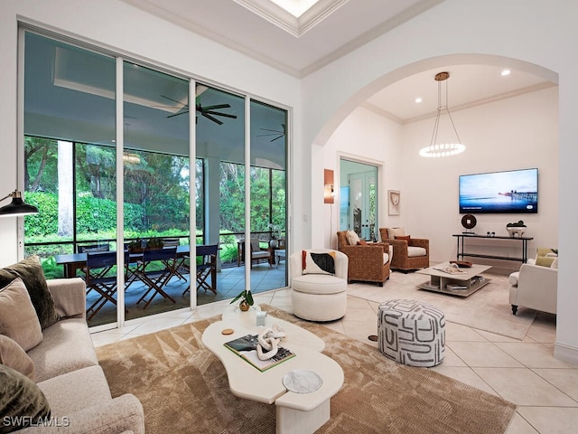 tiled living room featuring ornamental molding and ceiling fan with notable chandelier