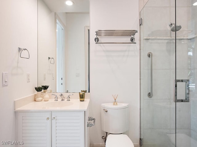 bathroom with vanity, a shower with door, and toilet