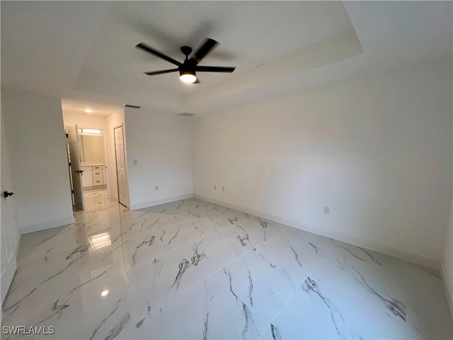 unfurnished bedroom with ceiling fan, a tray ceiling, and a closet