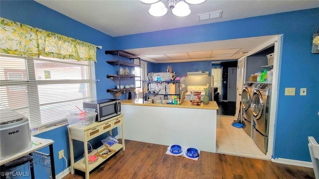 kitchen featuring butcher block counters, a notable chandelier, washer and dryer, and hardwood / wood-style flooring