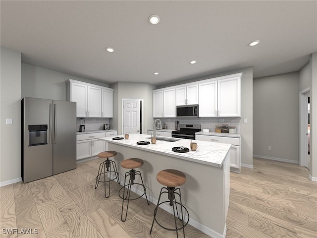 kitchen featuring backsplash, sink, white cabinetry, a kitchen island with sink, and stainless steel appliances