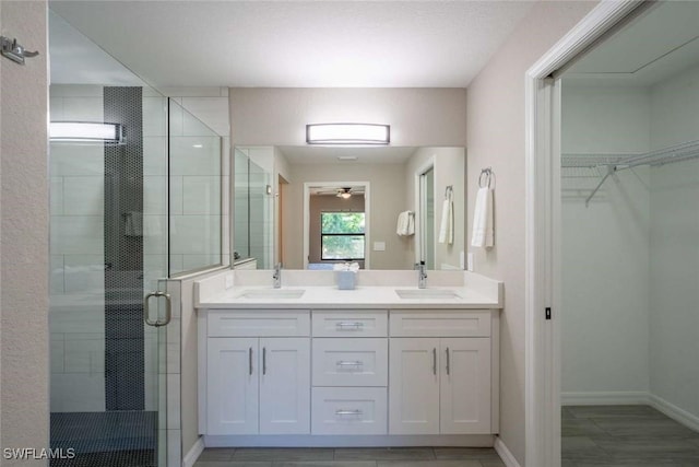 bathroom featuring a shower with shower door, vanity, and ceiling fan