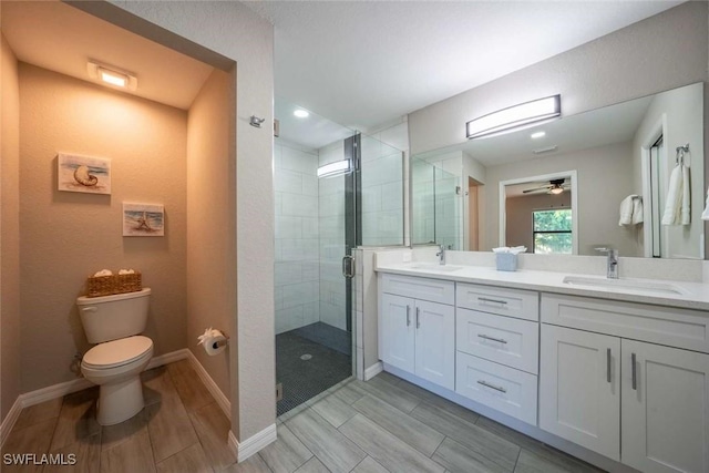 bathroom featuring a shower with door, toilet, vanity, and ceiling fan