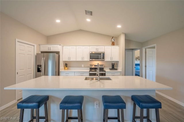 kitchen featuring a breakfast bar, sink, white cabinetry, appliances with stainless steel finishes, and a large island