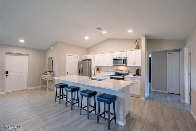 kitchen featuring white cabinetry, an island with sink, appliances with stainless steel finishes, a kitchen breakfast bar, and sink