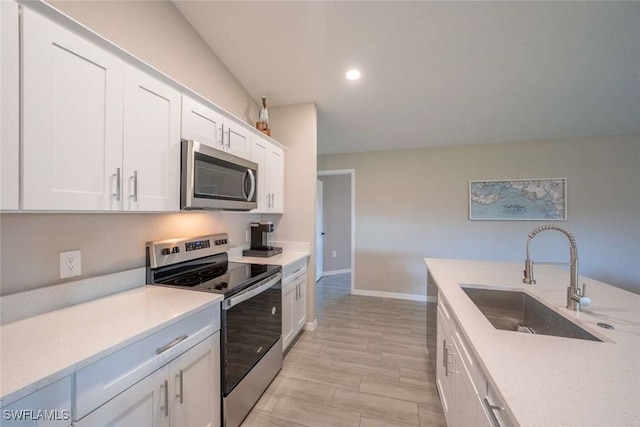 kitchen with appliances with stainless steel finishes, white cabinets, and sink