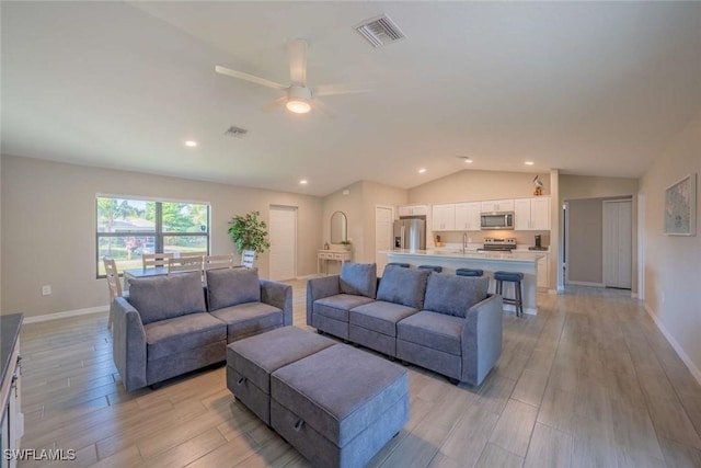 living room featuring ceiling fan, vaulted ceiling, and sink