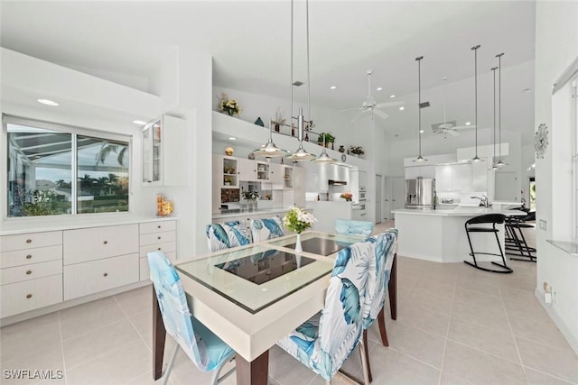 dining area with ceiling fan, light tile patterned floors, and high vaulted ceiling