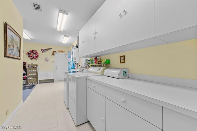 clothes washing area with washer and clothes dryer, light tile patterned floors, and cabinets