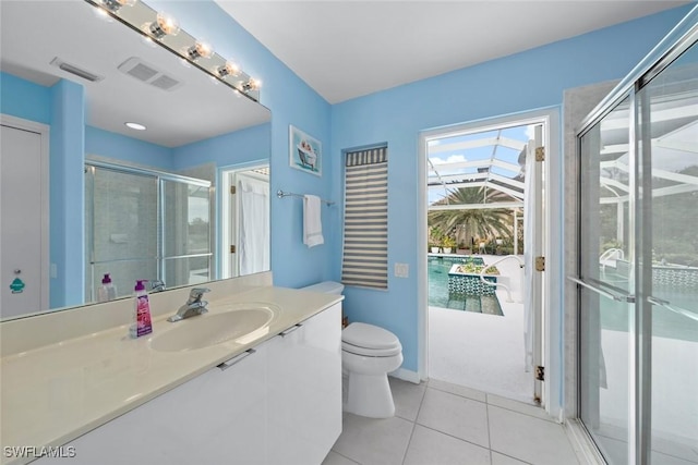 bathroom with a shower with shower door, toilet, vanity, and tile patterned flooring