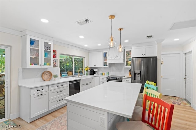 kitchen with hanging light fixtures, appliances with stainless steel finishes, a center island, and white cabinets