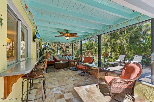 sunroom featuring beamed ceiling and ceiling fan