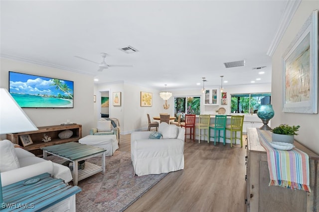 living room with crown molding, light hardwood / wood-style flooring, and ceiling fan