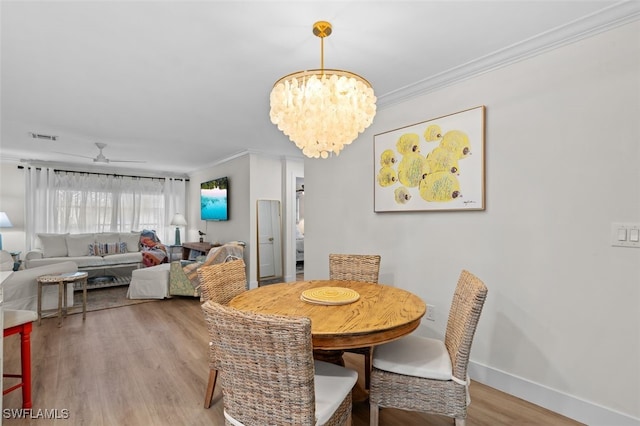 dining space featuring ceiling fan with notable chandelier, wood-type flooring, and ornamental molding