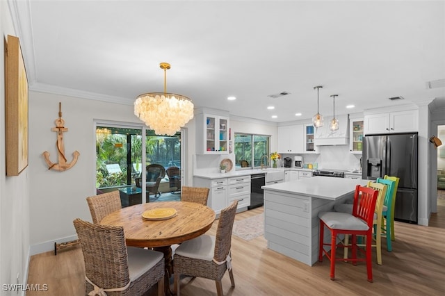 dining room featuring crown molding, sink, a notable chandelier, and light hardwood / wood-style flooring