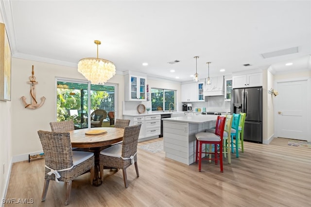 kitchen featuring pendant lighting, stainless steel fridge, ornamental molding, white cabinets, and a kitchen island