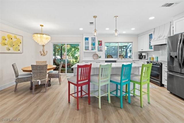 kitchen featuring appliances with stainless steel finishes, a center island, white cabinets, decorative light fixtures, and custom exhaust hood