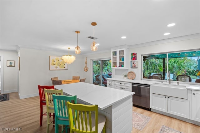 kitchen featuring decorative light fixtures, white cabinets, a kitchen breakfast bar, stainless steel dishwasher, and light stone countertops