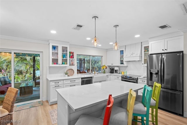 kitchen with a kitchen island, pendant lighting, a breakfast bar area, custom exhaust hood, and stainless steel appliances