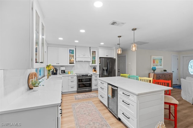 kitchen with a breakfast bar, white cabinetry, hanging light fixtures, stainless steel appliances, and a kitchen island