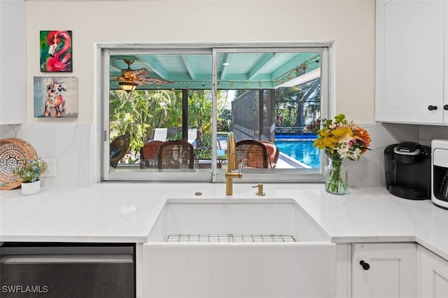 kitchen featuring white cabinetry, light stone countertops, dishwasher, and sink